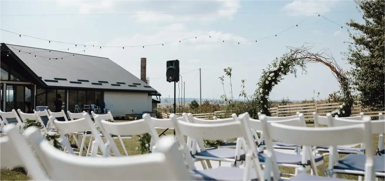 white chairs with a floral arch at a barn wedding